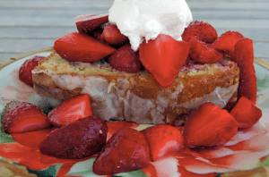 Photo of a Florida Orange Pound Cake topped with strawberries and whipped cream