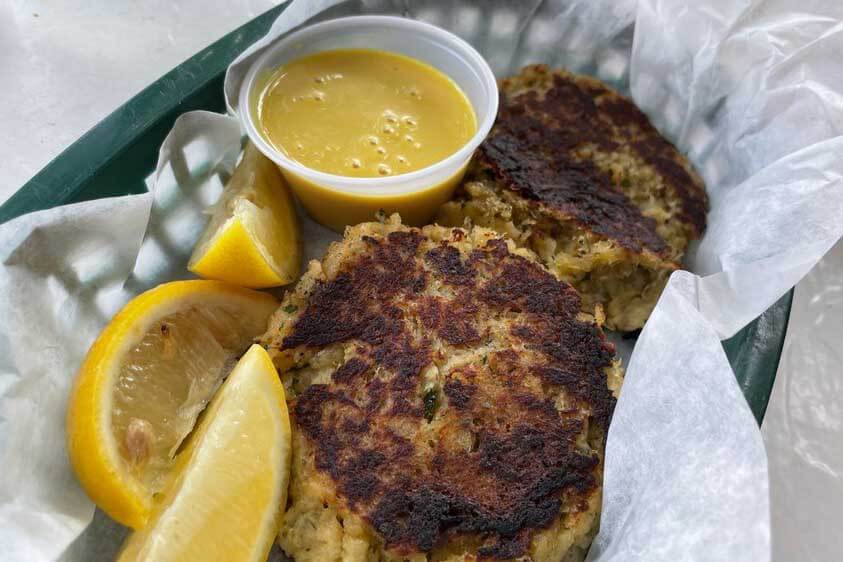 Conch fritters in a tray with sauce and lemons. 