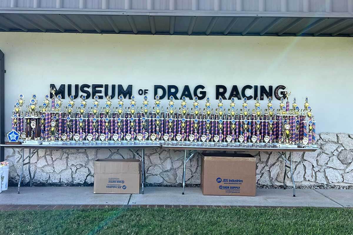 Don Garlits Museum of Drag Racing building exterior with trophies on a table. 