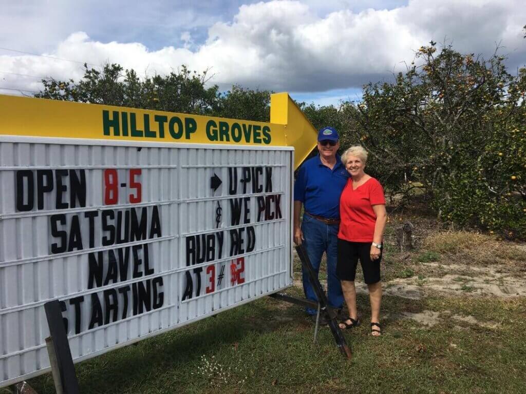 Owners in front of marquee sign to Hilltop Groves