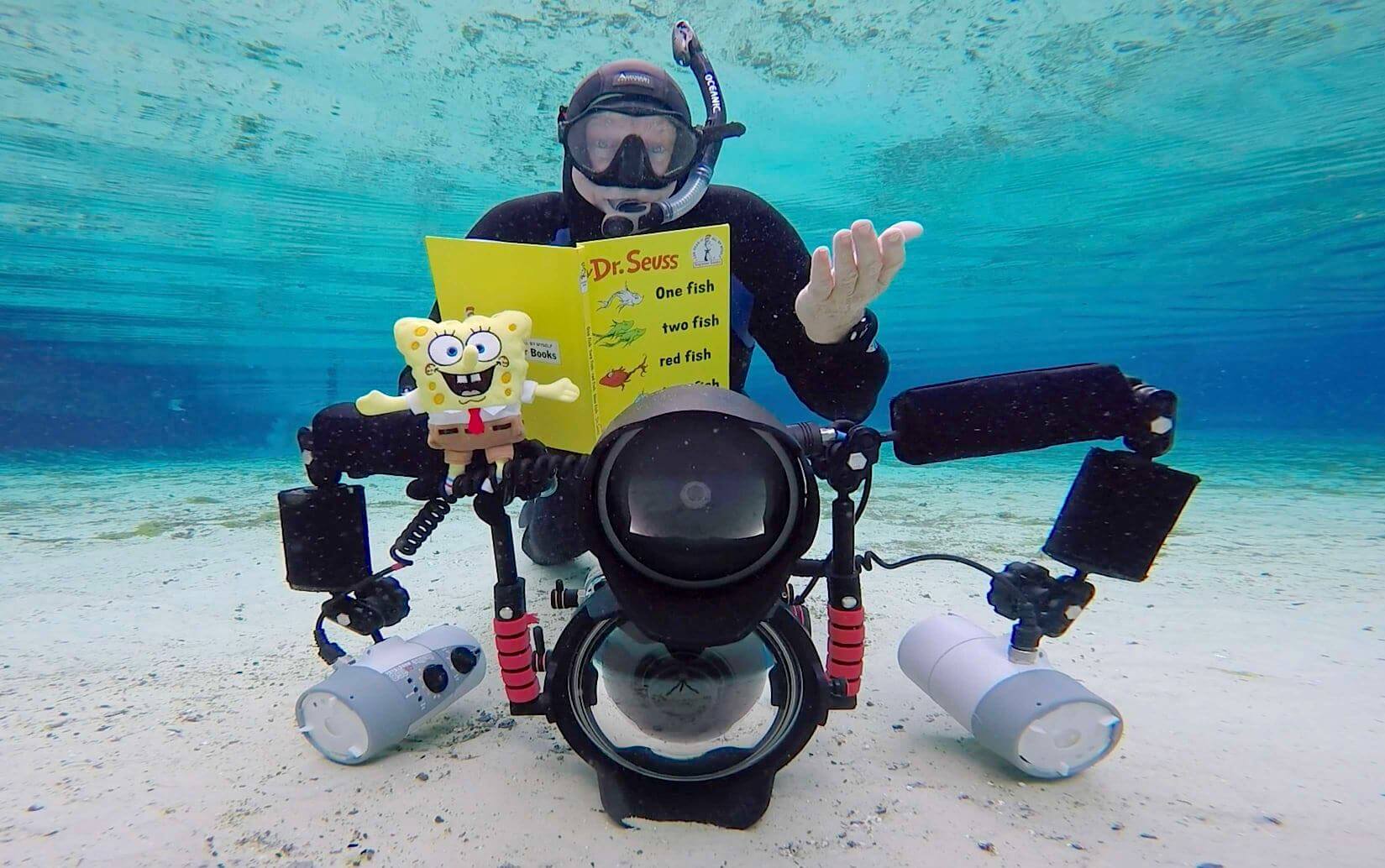 David Schrichte scuba diving with a camera and book.