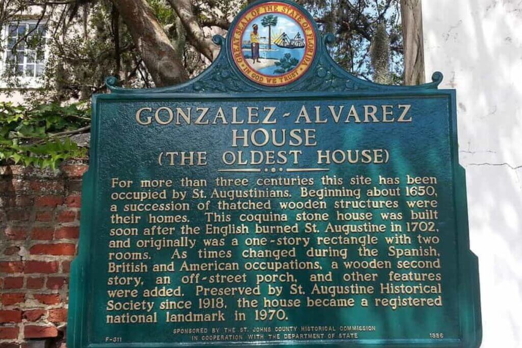 Sign that reads Gonzalez-Alvarez House (The Oldest House) For more than three centuries this site has been a succession of thatched wooden structures were their homes. this coquina stone house was built soon after the English burned St. Augustine in 1702, and orginally was a one-story rectangle with two rooms. As times changed during the Spanish, British, and American occupations, a wooden second story, an off-street porch, and other features were added. Preserved by St. Augustine Historical Society since 1918, the house became a registered national landmark in 1970. 