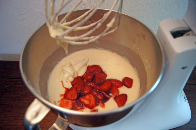 Adding cooked strawberries to the mixing bowl