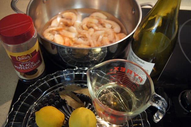 Shrimp in a pot with a variety of ingredients around. 