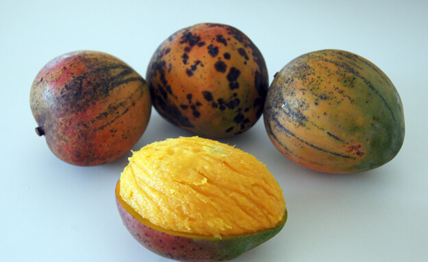 Mangos with a peeled mango in the front. 