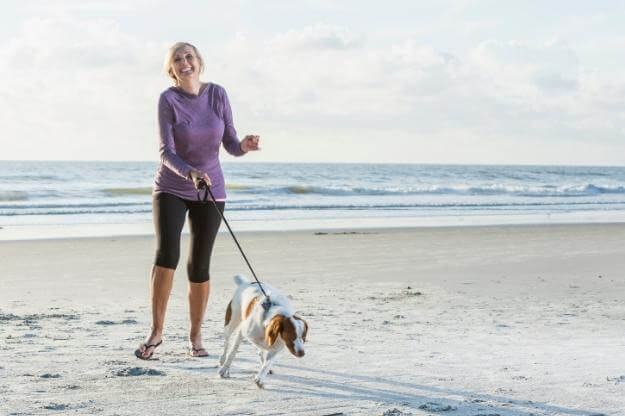 woman walking her dog on Florida dog-friendly beach.