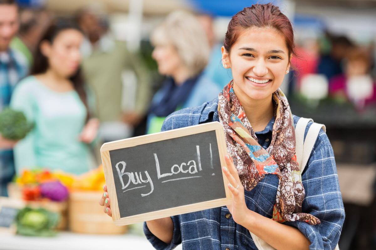 A young woman with a sign that says Buy Local.