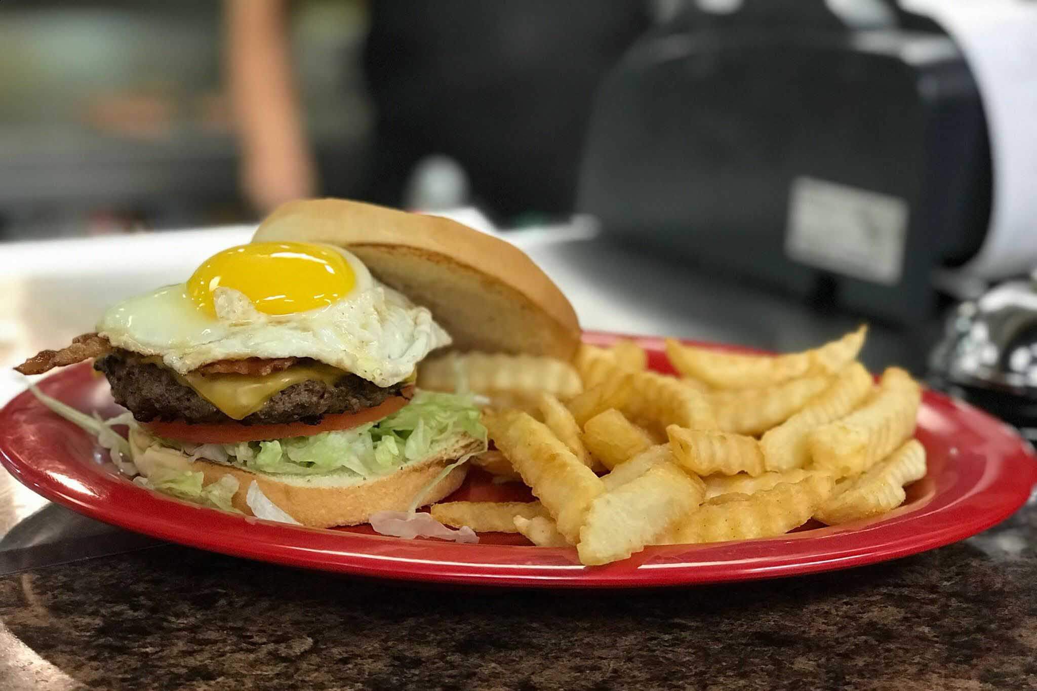 Cheeseburger with an egg on top and a side of fries. 