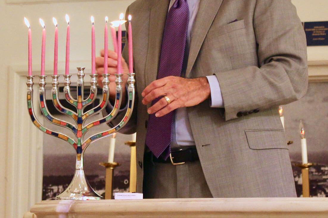 Man lighting a menorah at the Jewish Museum of Florida