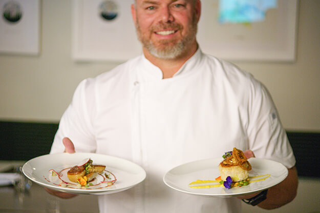 Photo of a chef holding plates of food