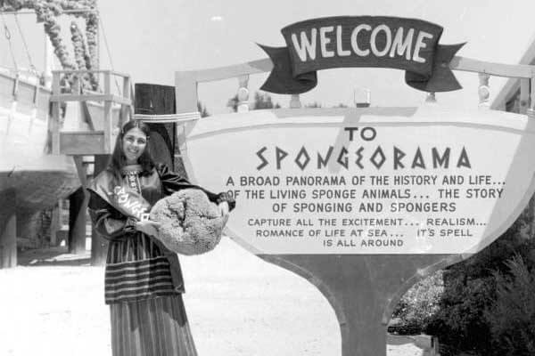 Woman holding sponge in front of Sponge Docks