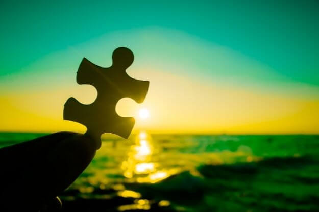 Photo of a puzzle piece being held over the ocean