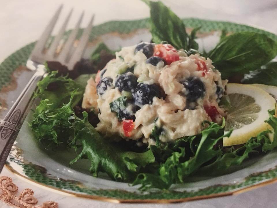 greens under a scoop of lemon blueberry chicken salad with a slice of lemon