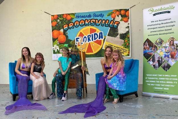 Photo of 2022 Florida Mermaid Trail Festival mermaids posing with kids in Brooksville