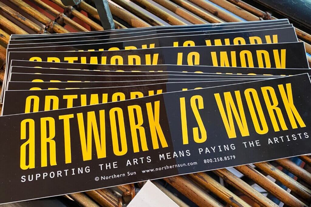 Artwork is Work bumper stickers at Village of the Arts. 