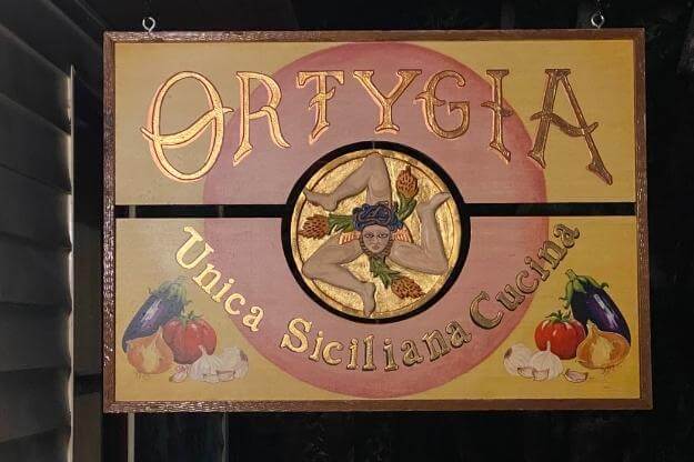 Sign that reads Ortygia Unica Siciliana Cucina. 