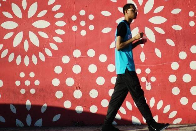 Photo of man walking in front of Wynwood wall during Art Basel