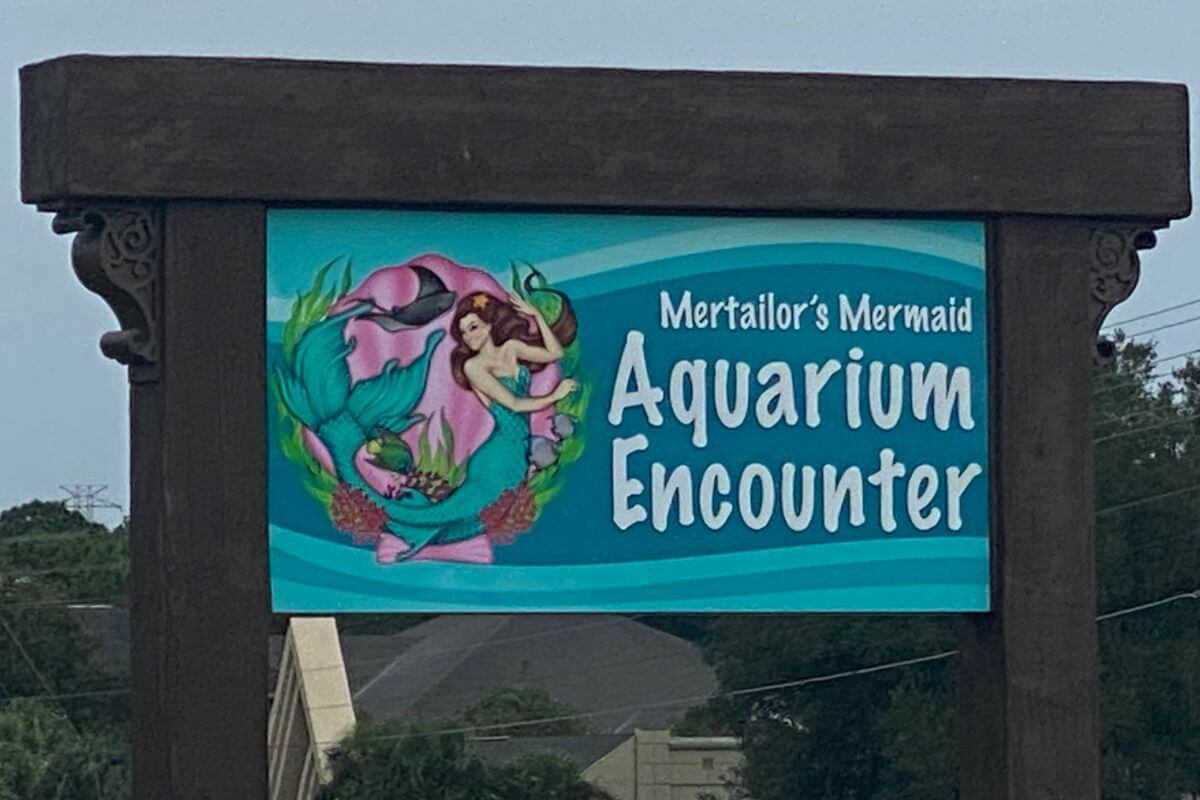 Sign reading Mertailor's Mermaid Aquarium Encounter. 