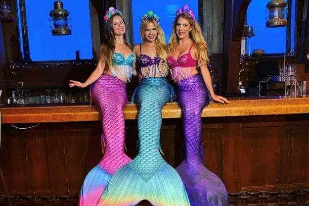 3 Mermaids sitting on a bar. 
