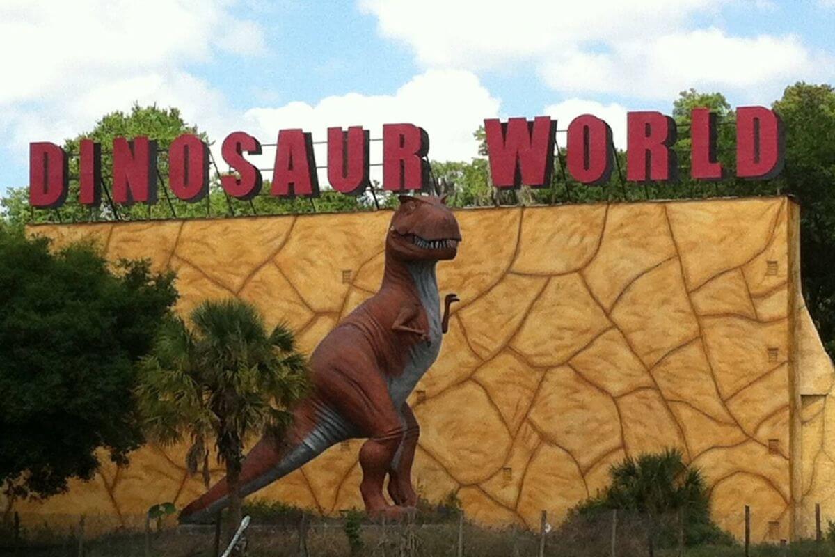 Dinosaur statue in  front of a sign that reads Dinosaur World. 