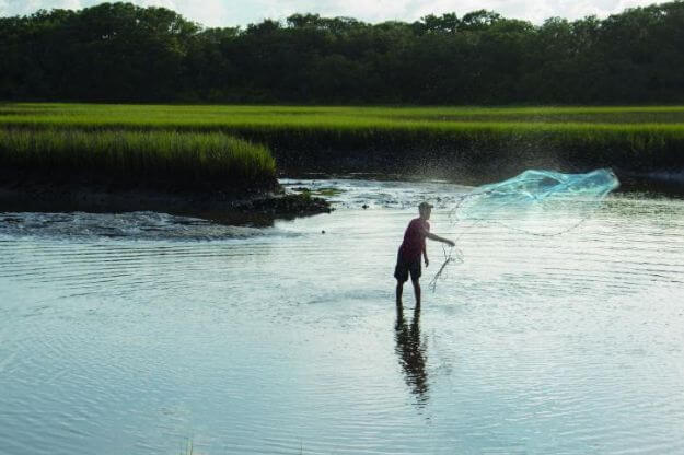 Person casting net in the water. 