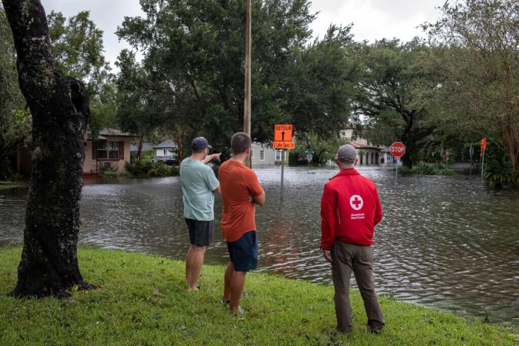 people standing in flooded neighborhood
