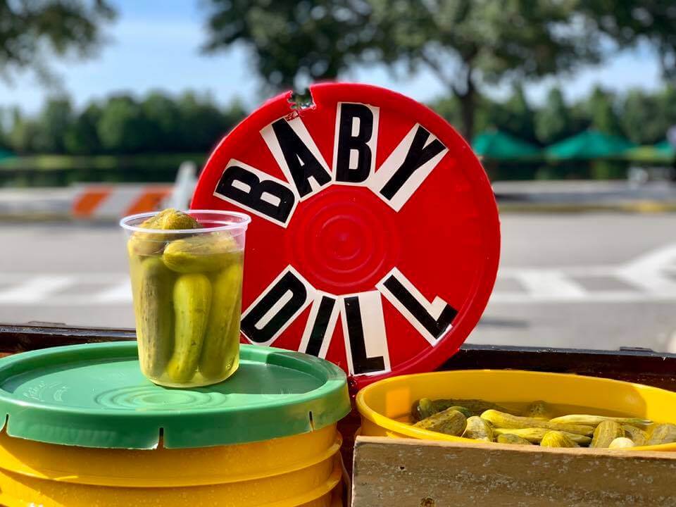 Pickles in a container with a lid with the words Baby Dill. 