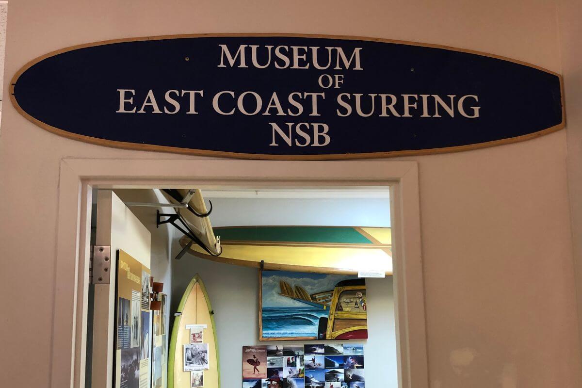 Interior of a building with a sign over the doorway that reads Museum of East Coast Surfing NSB. 