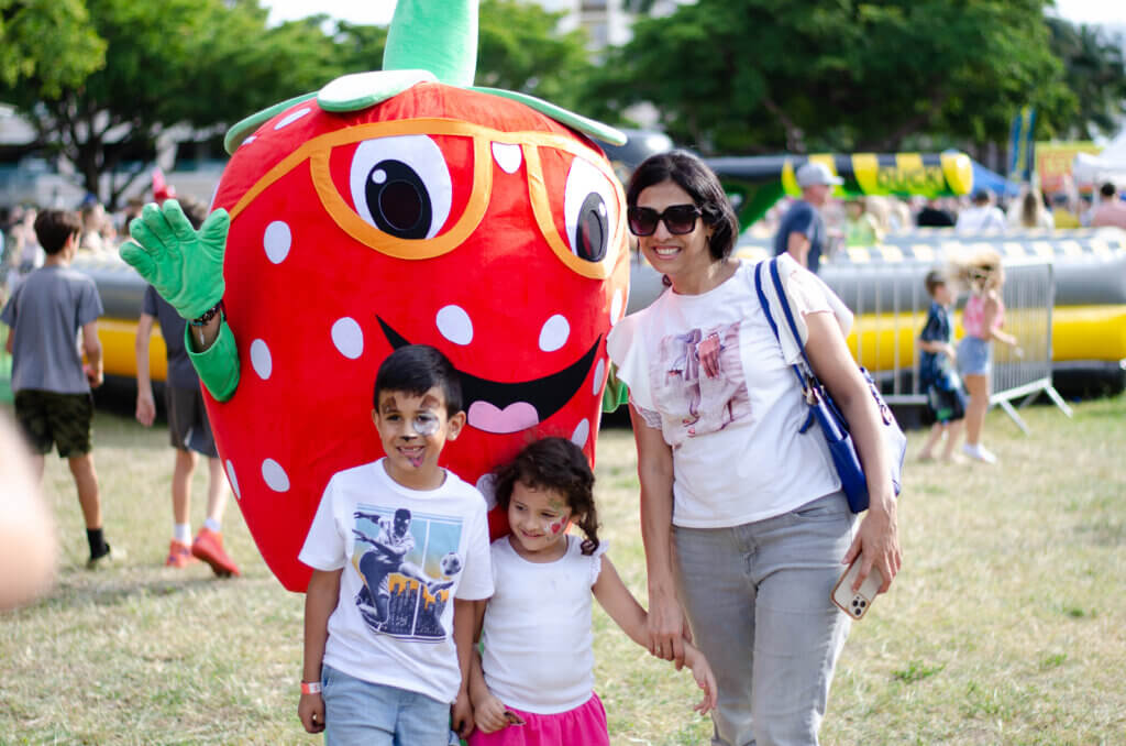 strawberry mascot with woman and two children