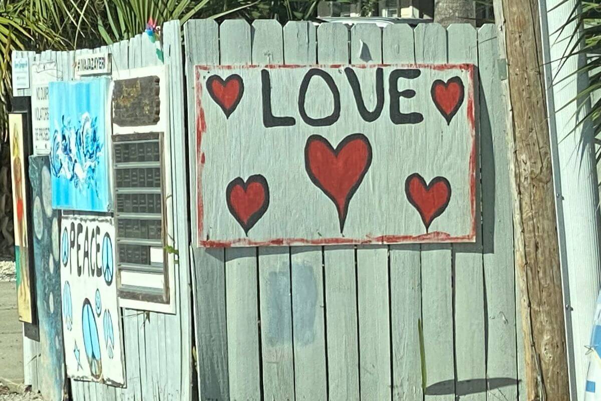 Sign that reads LOVE on a fence. 