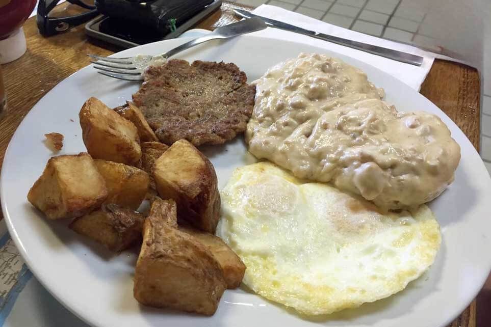 Sausage, hosue potatoes, sausage gravy, and eggs on a plate. 