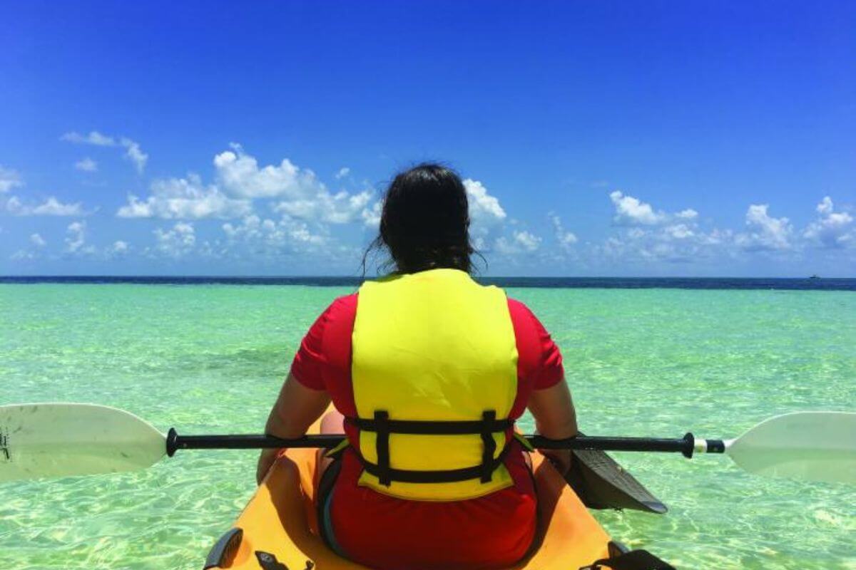 Person kayaking by beach.