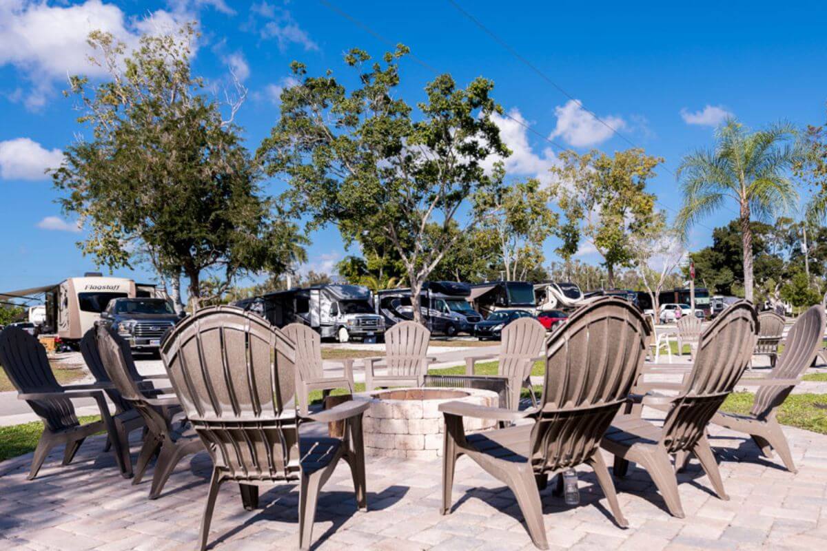 Group of lounge chairs around a fire pit near rv's. 