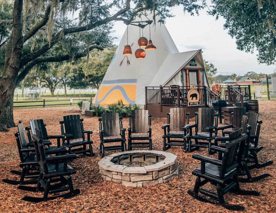 Camping tent behind rocking chairs surrounding a fire pit at Westgate River Ranch.