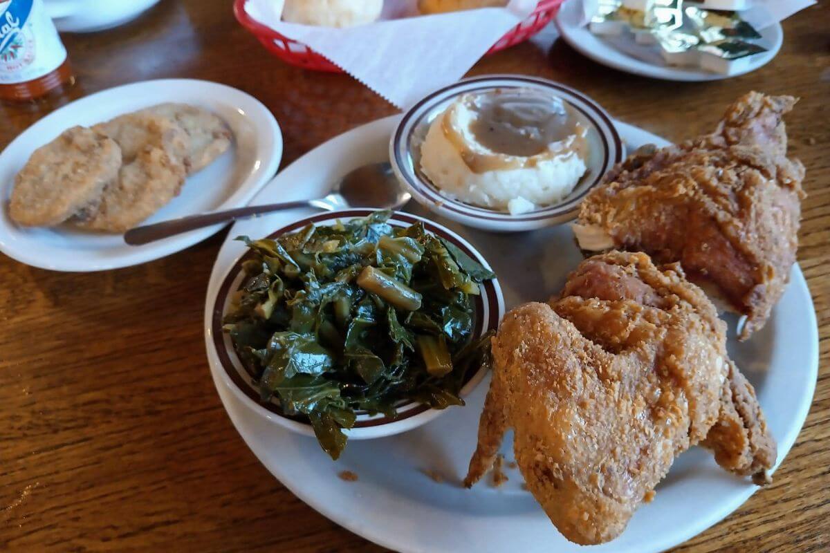 Fried chicken, greens, and mashed potatoes on a plate. 