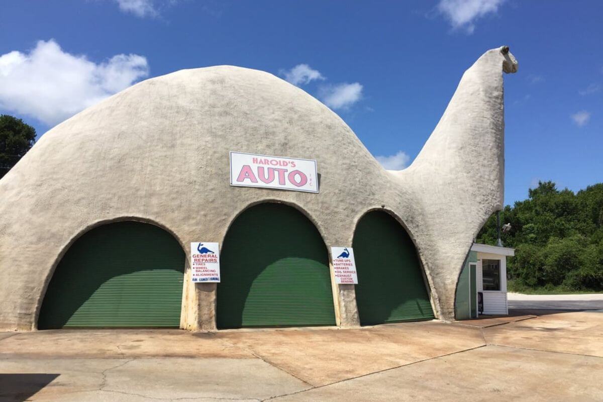 Dinosaur shaped building with a sign that reads Harold's Auto. 