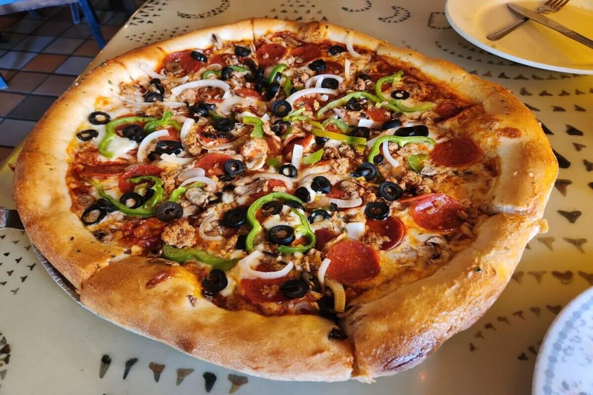 PIzza with toppings such as pepperoni, peppers, onions, and olives.