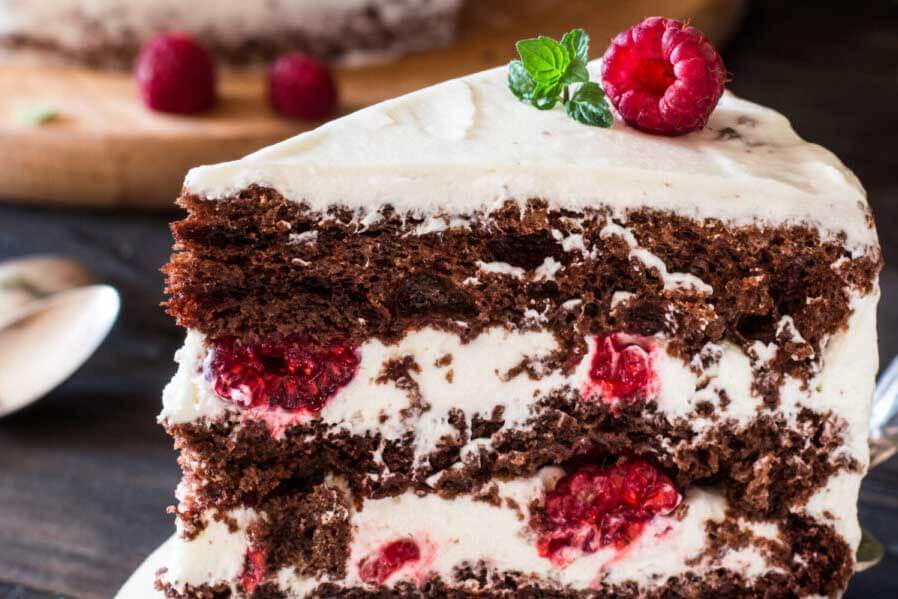 Layered Cake with raspberries in filling and a raspberry on top. 