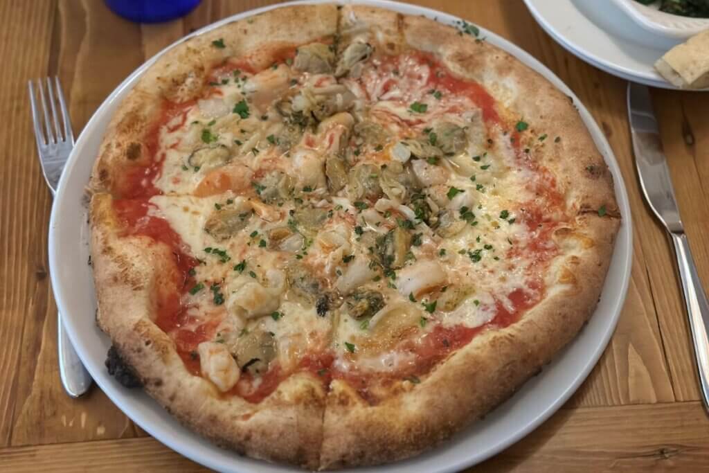 Simply Capri pizza with mozzarella, calamari, shrimps, clams, mussels, Parmigiano Reggiano, parsley and red sauce