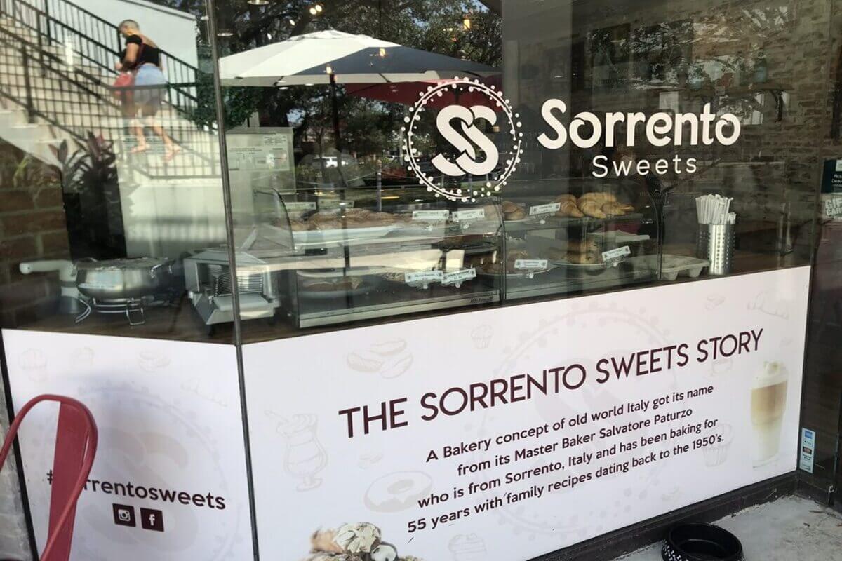 Exterior of a bakery with a window that reads Sorrento Sweets. 