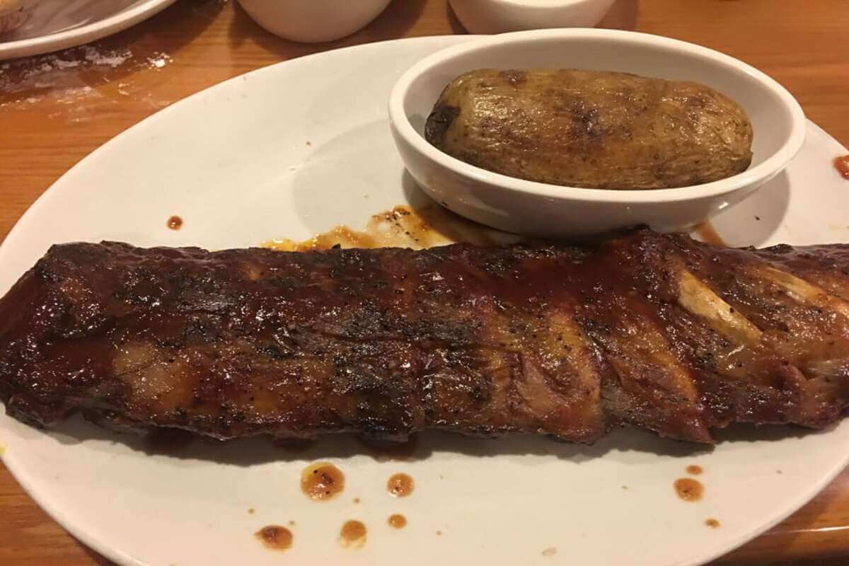 Ribs and a potato on a plate. 