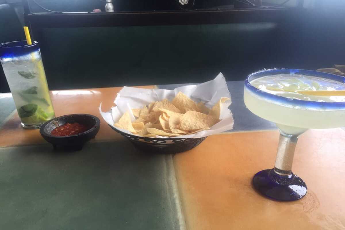 Chips in a bowl and drinks on a table. 