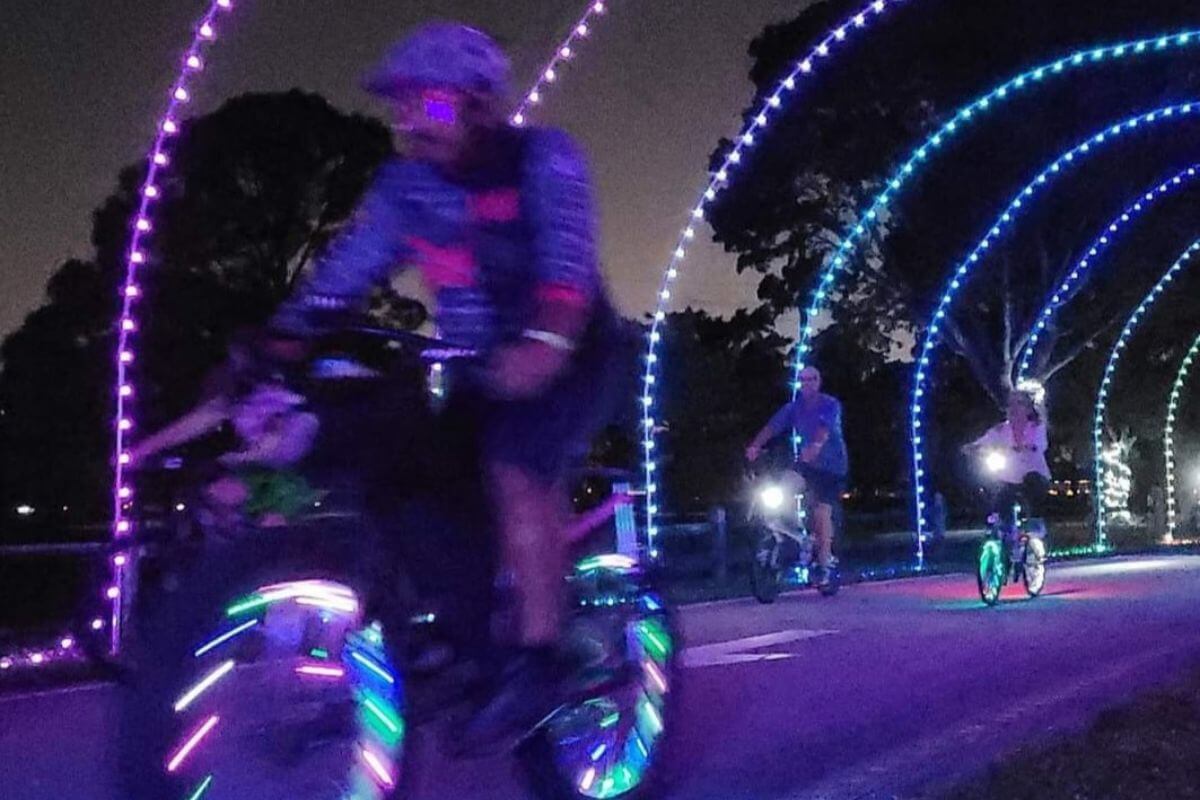 Bikers riding down a lighted trail. 