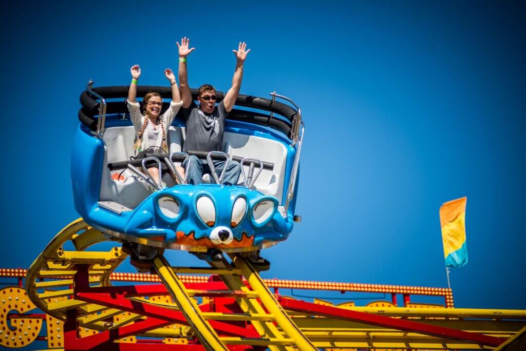 people putting hands in the air on a mouse trap ride